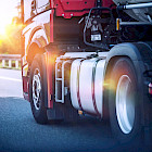 Roter Sattelzug fährt bei Sonnenuntergang auf der Autobahn
