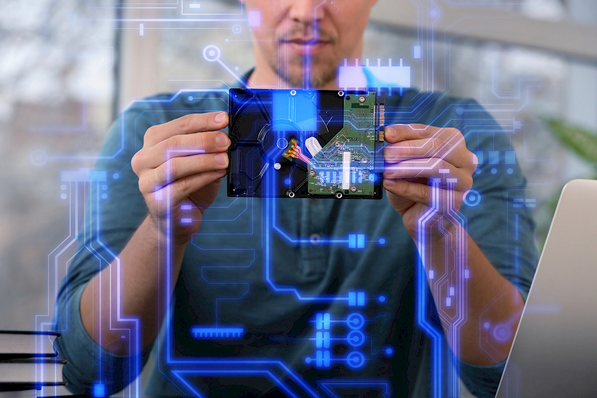 Mann hält eine Platine vor leuchtenden digitalen Schaltkreisen