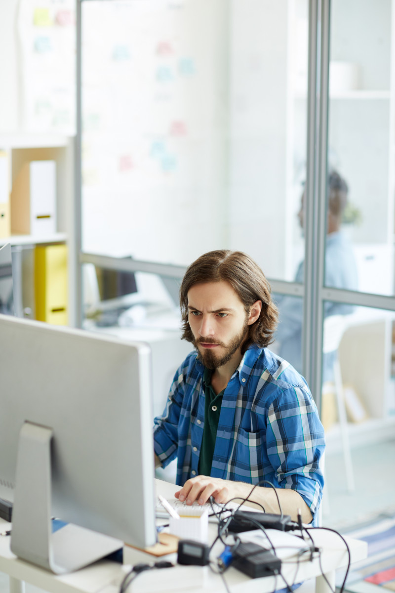 Junger Mann arbeitet konzentriert am Computer in einem Büro